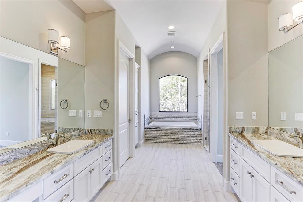 This is an example of a large contemporary ensuite bathroom in Houston with shaker cabinets, white cabinets, an alcove bath, an alcove shower, a two-piece toilet, grey tiles, stone slabs, grey walls, ceramic flooring, a submerged sink, marble worktops, grey floors, a hinged door and beige worktops.