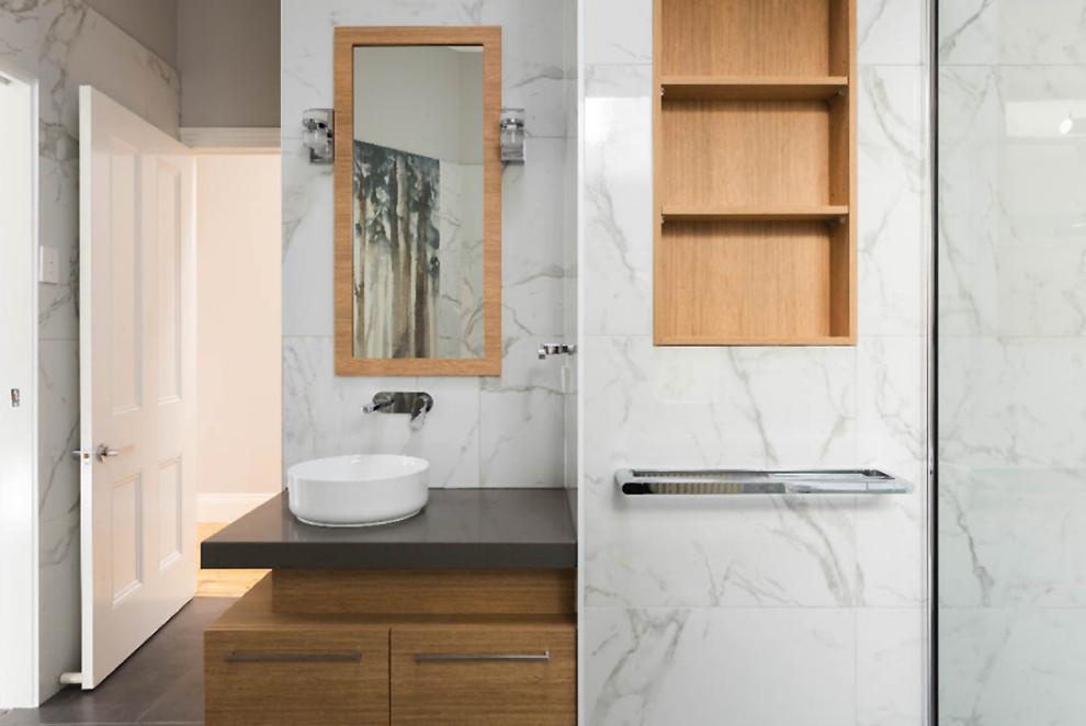 Large beach style ensuite bathroom in Melbourne with a freestanding bath, a corner shower, a two-piece toilet, white tiles, marble tiles, grey walls, ceramic flooring, a vessel sink, engineered stone worktops, grey floors, grey worktops, a wall niche, a single sink, a built in vanity unit and wainscoting.