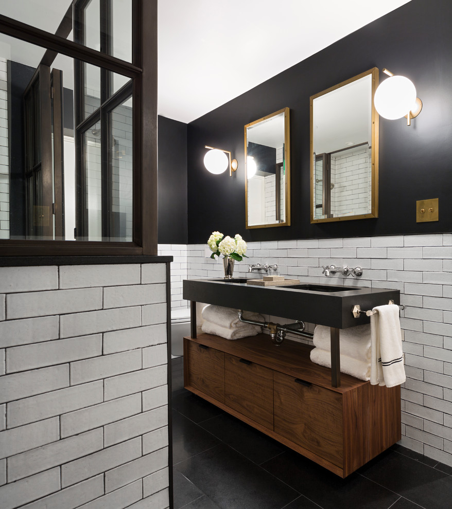 Cette image montre une salle de bain principale traditionnelle en bois brun avec un placard à porte plane, un mur noir, un lavabo intégré et une cabine de douche à porte battante.