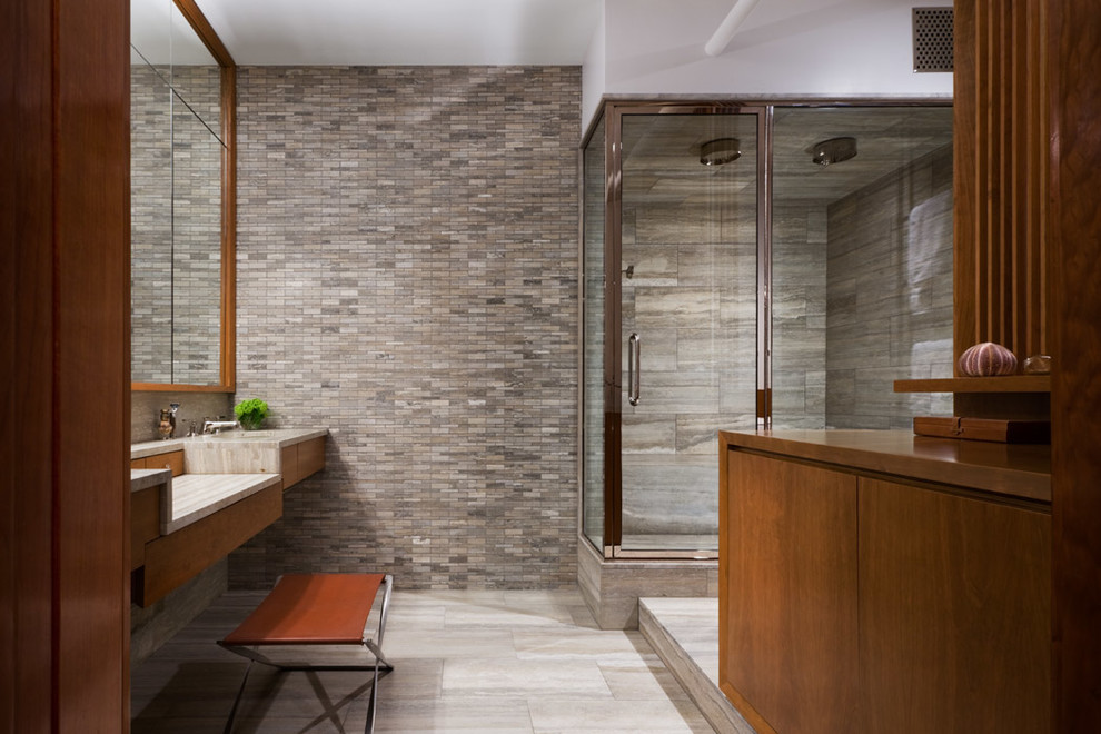 Modelo de cuarto de baño contemporáneo con puertas de armario de madera oscura, baldosas y/o azulejos grises, paredes grises, ducha esquinera y azulejos en listel