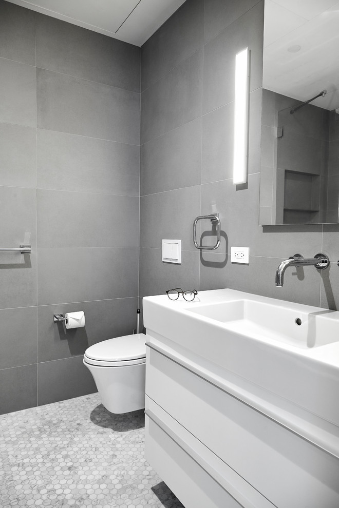 Bild på ett litet funkis en-suite badrum, med släta luckor, vita skåp, en toalettstol med hel cisternkåpa, grå kakel, porslinskakel, marmorgolv, ett integrerad handfat, en öppen dusch, grå väggar, bänkskiva i akrylsten, vitt golv och dusch med gångjärnsdörr