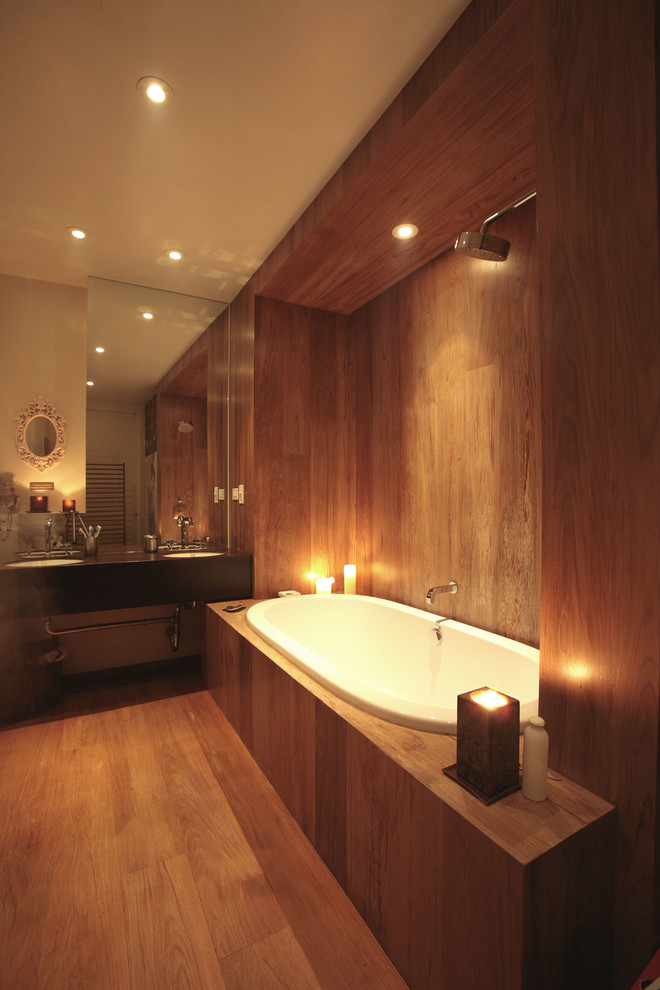 Modernes Badezimmer mit Einbaubadewanne und braunem Holzboden in New York