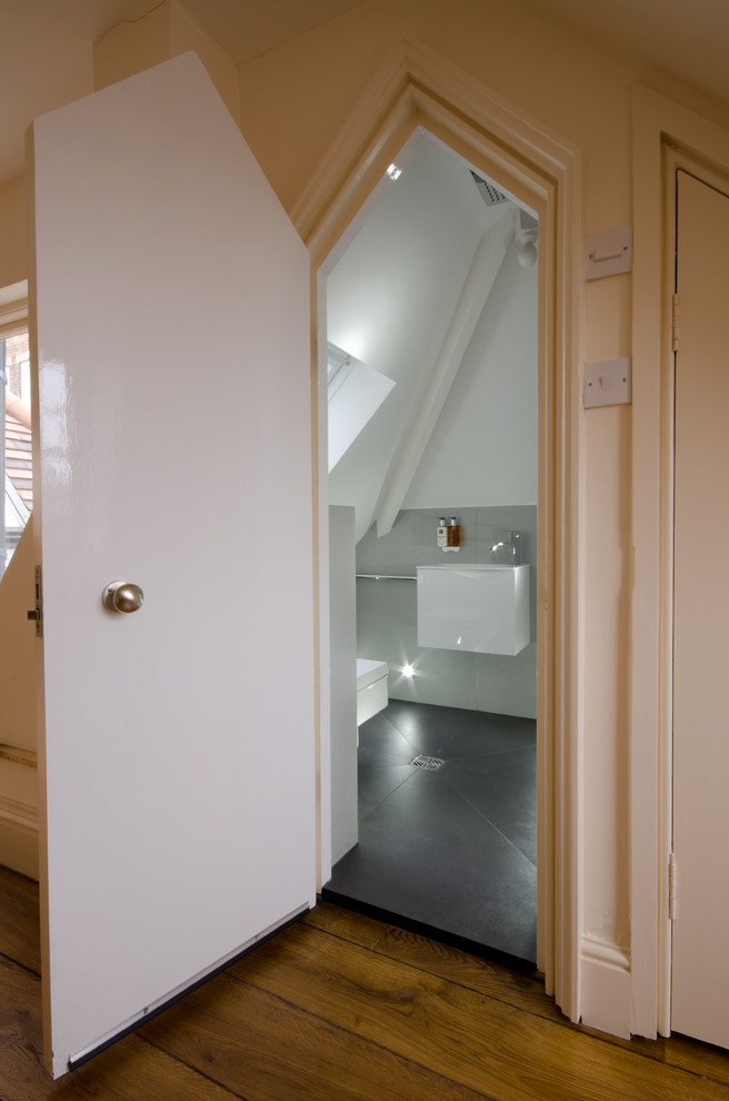 Exemple d'une petite salle de bain principale tendance avec un placard à porte vitrée, des portes de placard blanches, une douche ouverte, WC suspendus, un carrelage gris, des carreaux de porcelaine, un mur gris, un sol en carrelage de porcelaine et un lavabo suspendu.