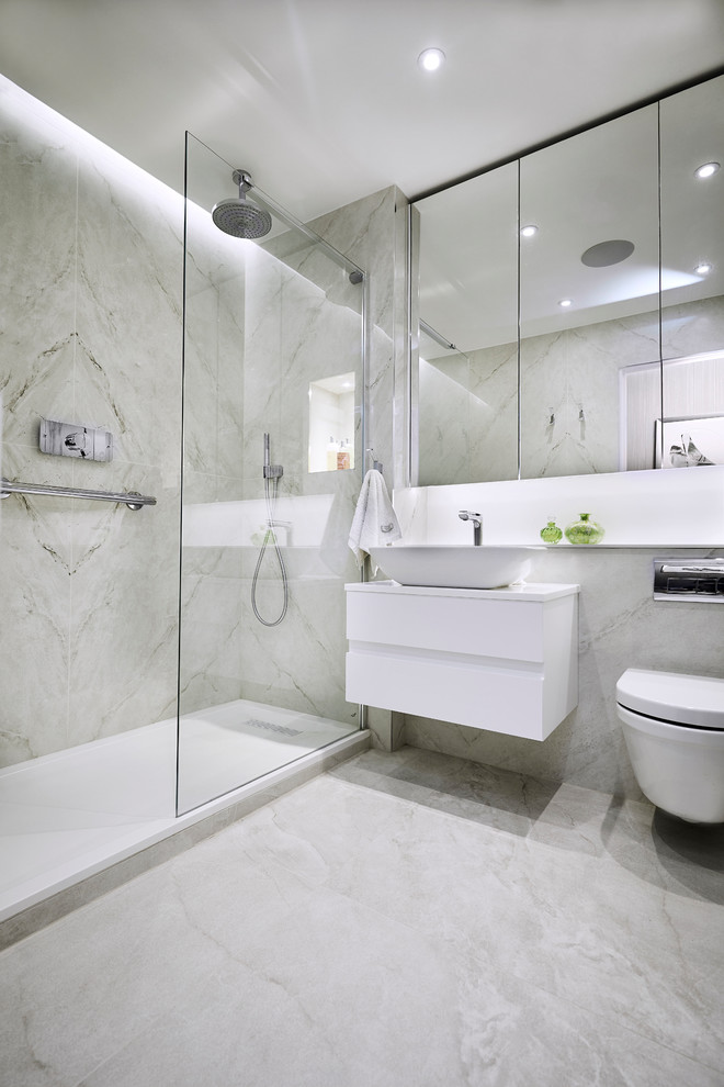 Inspiration för mellanstora moderna en-suite badrum, med släta luckor, vita skåp, en öppen dusch, en vägghängd toalettstol, vit kakel, porslinskakel, vita väggar, klinkergolv i porslin, ett väggmonterat handfat, bänkskiva i akrylsten, vitt golv och med dusch som är öppen
