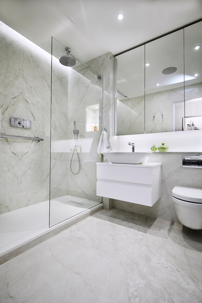 This is an example of a medium sized modern ensuite bathroom in London with glass-front cabinets, a walk-in shower, a wall mounted toilet, grey tiles, marble tiles, marble flooring, a wall-mounted sink, quartz worktops and a hinged door.