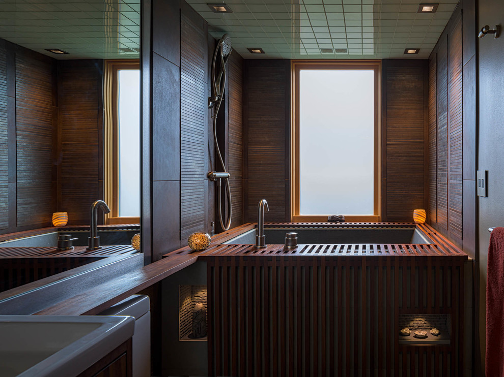 Стильный дизайн: ванная комната среднего размера в стиле модернизм с фасадами островного типа, темными деревянными фасадами, японской ванной, душевой комнатой, унитазом-моноблоком, коричневой плиткой, керамогранитной плиткой, серыми стенами, полом из керамогранита, накладной раковиной, столешницей из дерева, зеленым полом и открытым душем - последний тренд