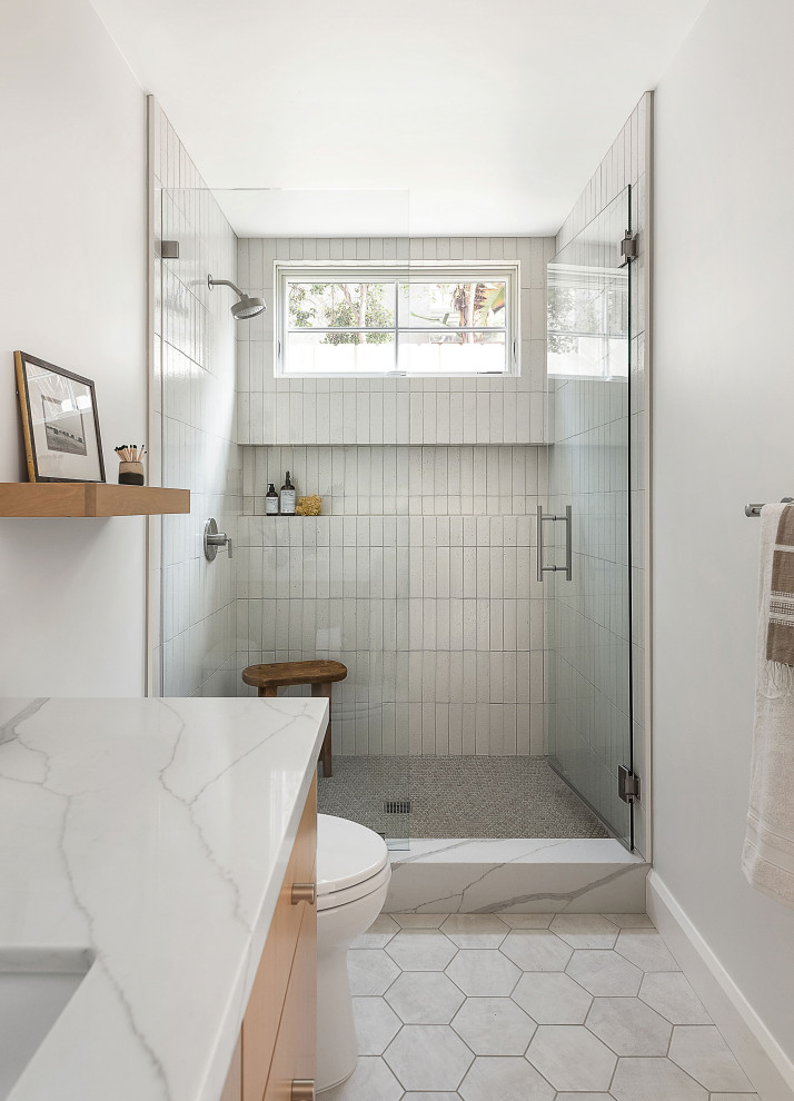 Пример оригинального дизайна: ванная комната среднего размера в стиле кантри с плоскими фасадами, светлыми деревянными фасадами, белой плиткой, терракотовой плиткой, врезной раковиной, столешницей из искусственного кварца, душем с распашными дверями, белой столешницей, душем в нише, серыми стенами, белым полом и нишей