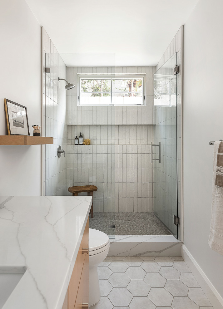 Inspiration for a mid-sized country white tile and terra-cotta tile white floor alcove shower remodel in San Diego with flat-panel cabinets, light wood cabinets, an undermount sink, quartz countertops, a hinged shower door, white countertops, gray walls and a niche