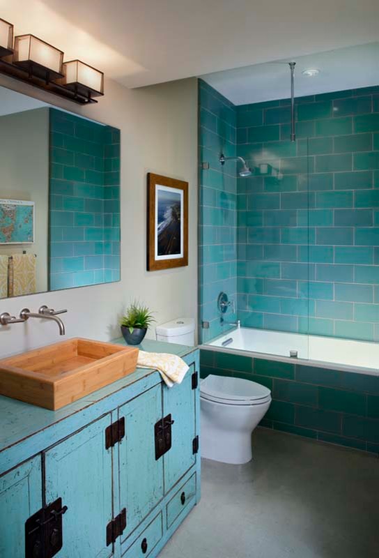 Идея дизайна: главная ванная комната среднего размера в стиле фьюжн с плоскими фасадами, искусственно-состаренными фасадами, ванной в нише, душем над ванной, раздельным унитазом, синей плиткой, керамической плиткой, серыми стенами, бетонным полом, настольной раковиной, столешницей из дерева и бирюзовой столешницей