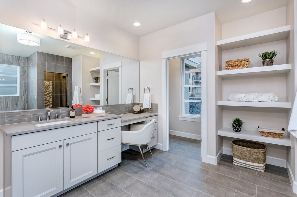 Photo of a classic ensuite bathroom in Seattle with recessed-panel cabinets, white cabinets, grey tiles, beige walls, a submerged sink, grey floors and grey worktops.