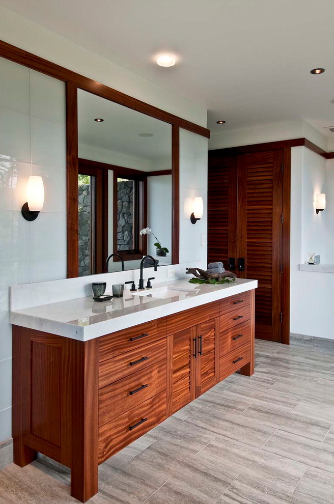 Diseño de cuarto de baño exótico con lavabo bajoencimera, armarios con paneles lisos, puertas de armario de madera oscura y baldosas y/o azulejos blancos