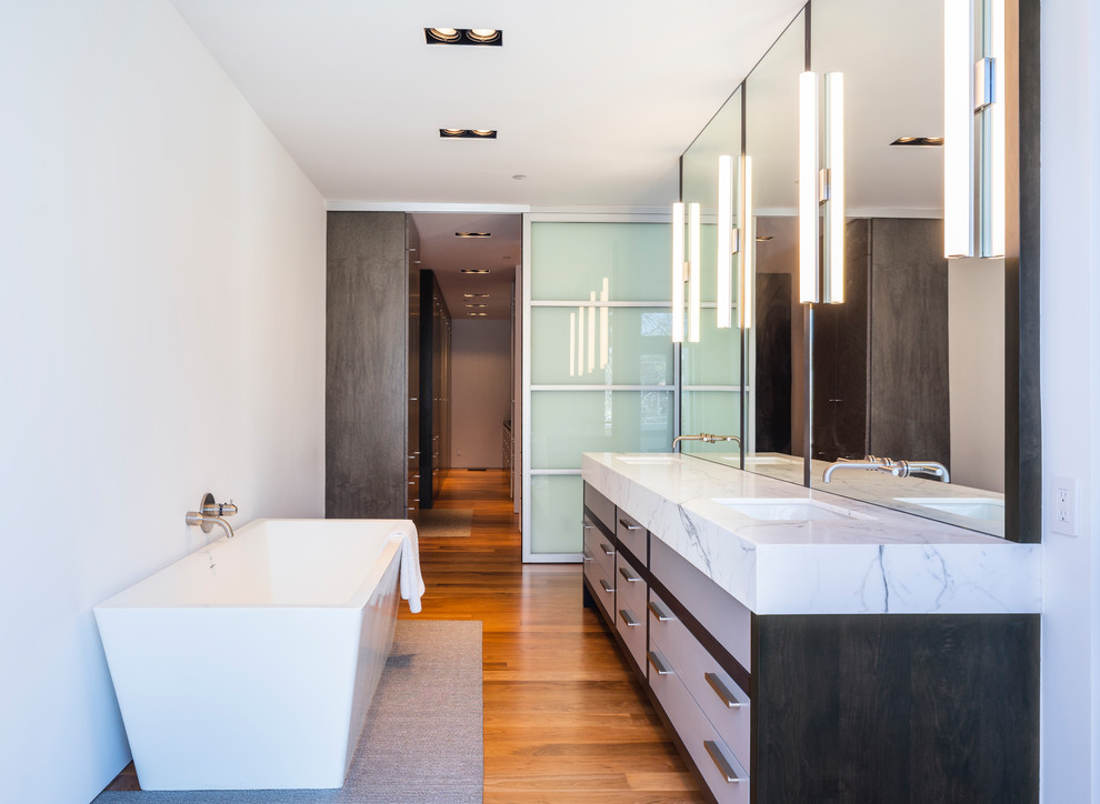 Immagine di una stanza da bagno padronale moderna con consolle stile comò, pareti bianche, pavimento in legno verniciato, lavabo sottopiano e top in marmo