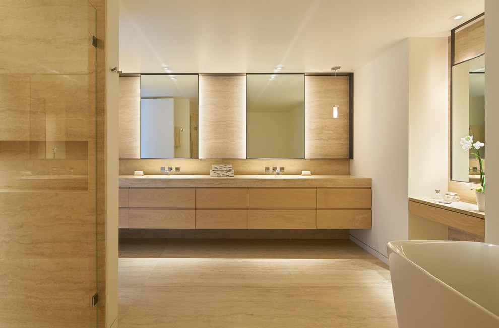 Foto på ett funkis en-suite badrum, med släta luckor, skåp i ljust trä, ett fristående badkar, travertinkakel, vita väggar, travertin golv och ett undermonterad handfat