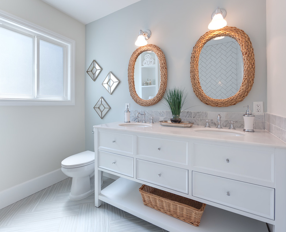 Cette image montre une salle de bain traditionnelle avec un lavabo encastré, un placard avec porte à panneau encastré, des portes de placard blanches, WC séparés, un carrelage de pierre, un mur gris et un sol en carrelage de céramique.