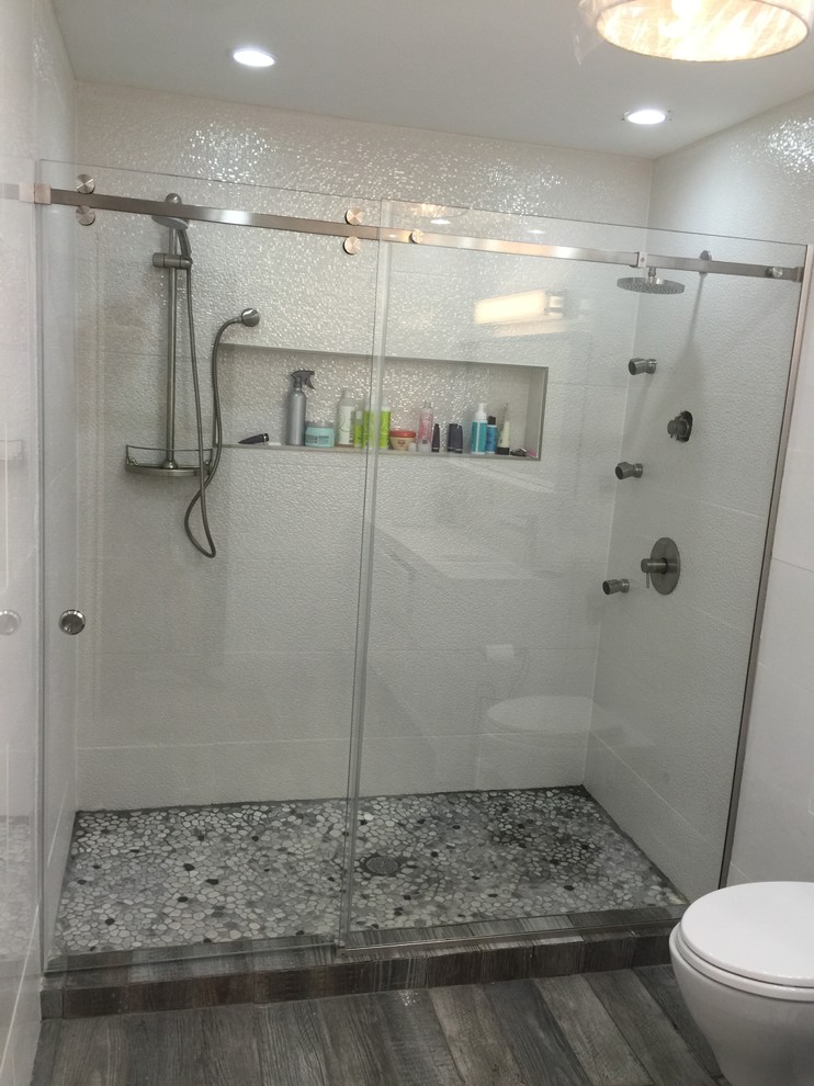 Imagen de cuarto de baño principal minimalista de tamaño medio con armarios abiertos, bañera esquinera, combinación de ducha y bañera, baldosas y/o azulejos de cemento, encimera de vidrio y ducha abierta