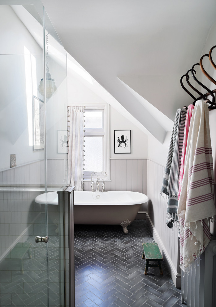 Inredning av ett klassiskt badrum med dusch, med ett badkar med tassar, vita väggar, grått golv och dusch med gångjärnsdörr