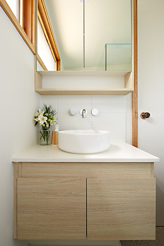 Exemple d'une petite salle d'eau bord de mer en bois clair avec un placard à porte plane, une douche d'angle, WC suspendus, des carreaux de céramique, un sol en carrelage de terre cuite, une vasque et un plan de toilette en surface solide.