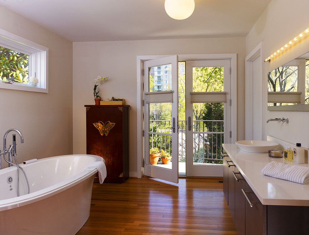 На фото: ванная комната в современном стиле с отдельно стоящей ванной, настольной раковиной и белой столешницей с