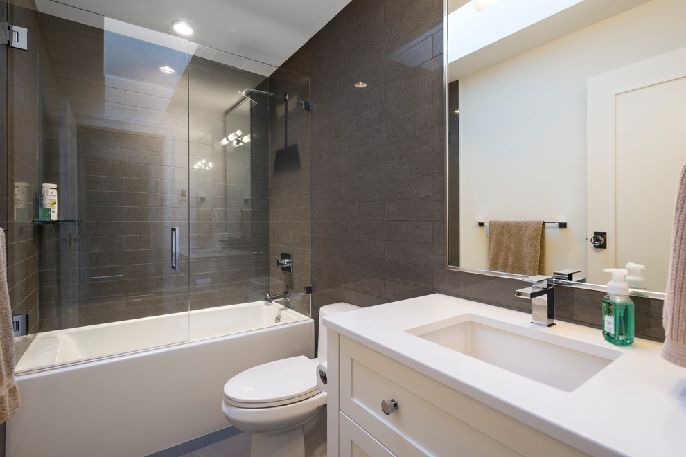 Inredning av ett klassiskt stort badrum med dusch, med skåp i shakerstil, vita skåp, ett badkar i en alkov, en dusch/badkar-kombination, en toalettstol med hel cisternkåpa, grå kakel, porslinskakel, vita väggar, klinkergolv i porslin, ett undermonterad handfat, bänkskiva i kvarts, grått golv och dusch med gångjärnsdörr