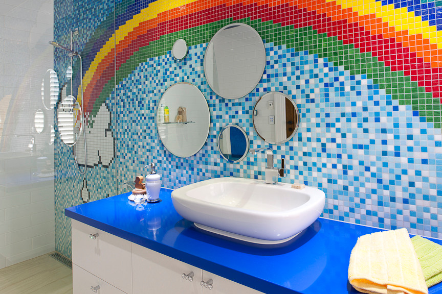 Réalisation d'une grande salle de bain design pour enfant avec un placard à porte plane, des portes de placard blanches, un plan de toilette en surface solide et un carrelage multicolore.