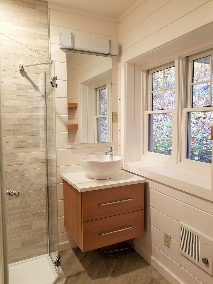 Example of a small farmhouse gray tile and stone tile porcelain tile and gray floor corner shower design in Jacksonville with flat-panel cabinets, medium tone wood cabinets, white walls, a vessel sink, quartz countertops, a hinged shower door and white countertops
