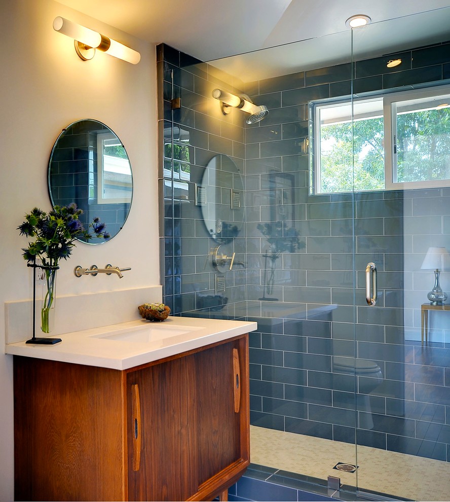 Cette photo montre une douche en alcôve rétro en bois brun avec un carrelage bleu, un carrelage en pâte de verre, un lavabo encastré et un placard à porte plane.