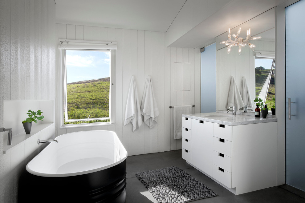 Foto de cuarto de baño de estilo de casa de campo con lavabo bajoencimera, armarios con paneles lisos, puertas de armario blancas, bañera exenta y paredes blancas