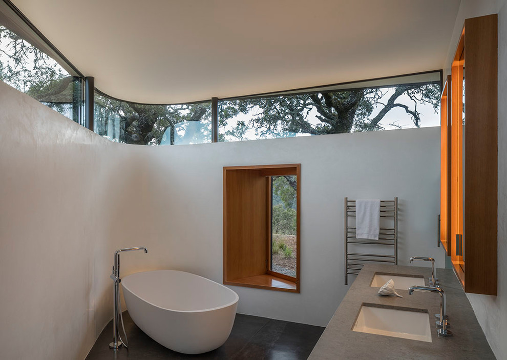 This is an example of a large modern ensuite bathroom in San Francisco with a freestanding bath, concrete flooring, a submerged sink and grey floors.