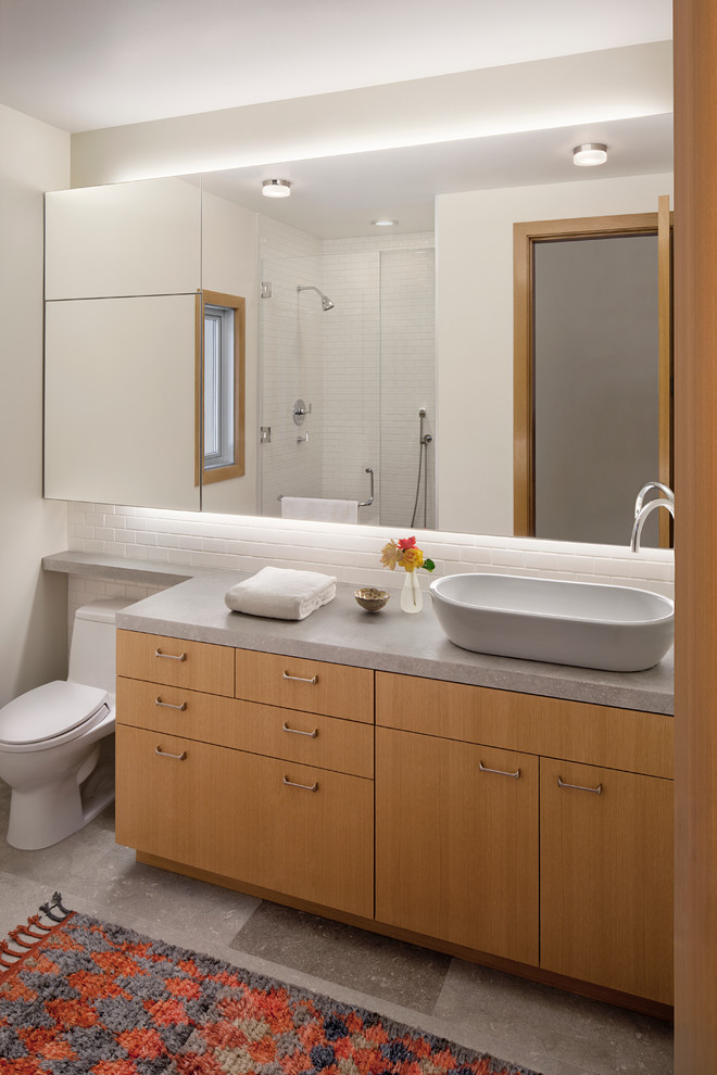 Example of a large trendy 3/4 white tile and porcelain tile concrete floor alcove shower design in San Francisco with flat-panel cabinets, light wood cabinets, a one-piece toilet, white walls, a vessel sink and concrete countertops