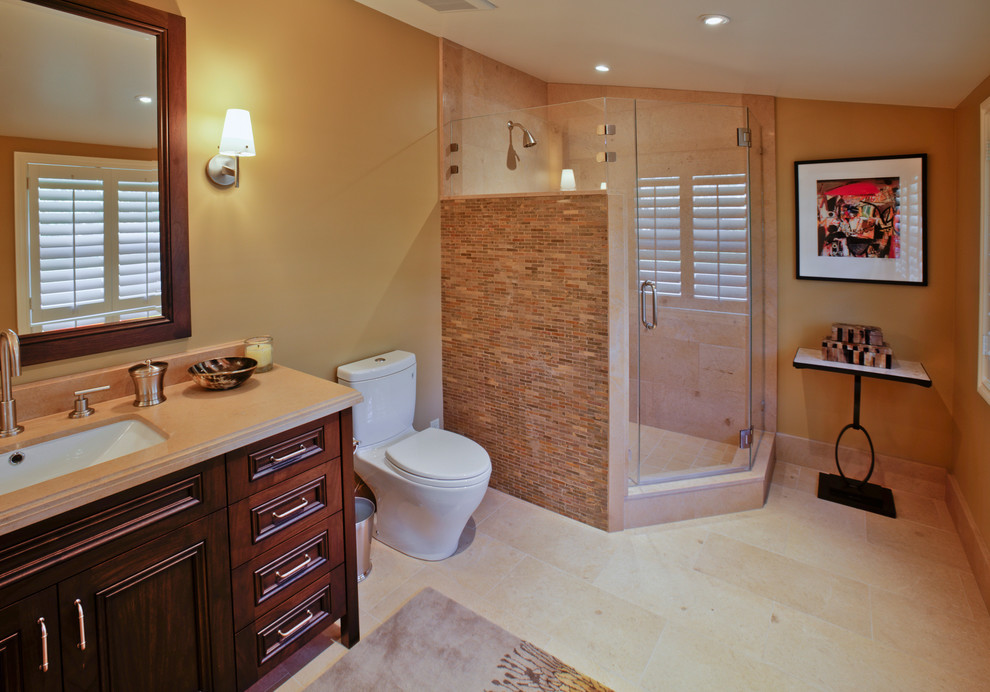Photo of a medium sized classic shower room bathroom in San Francisco with a submerged sink, shaker cabinets, dark wood cabinets, limestone worktops, an alcove bath, a shower/bath combination, a one-piece toilet, beige tiles, glass tiles, beige walls and limestone flooring.