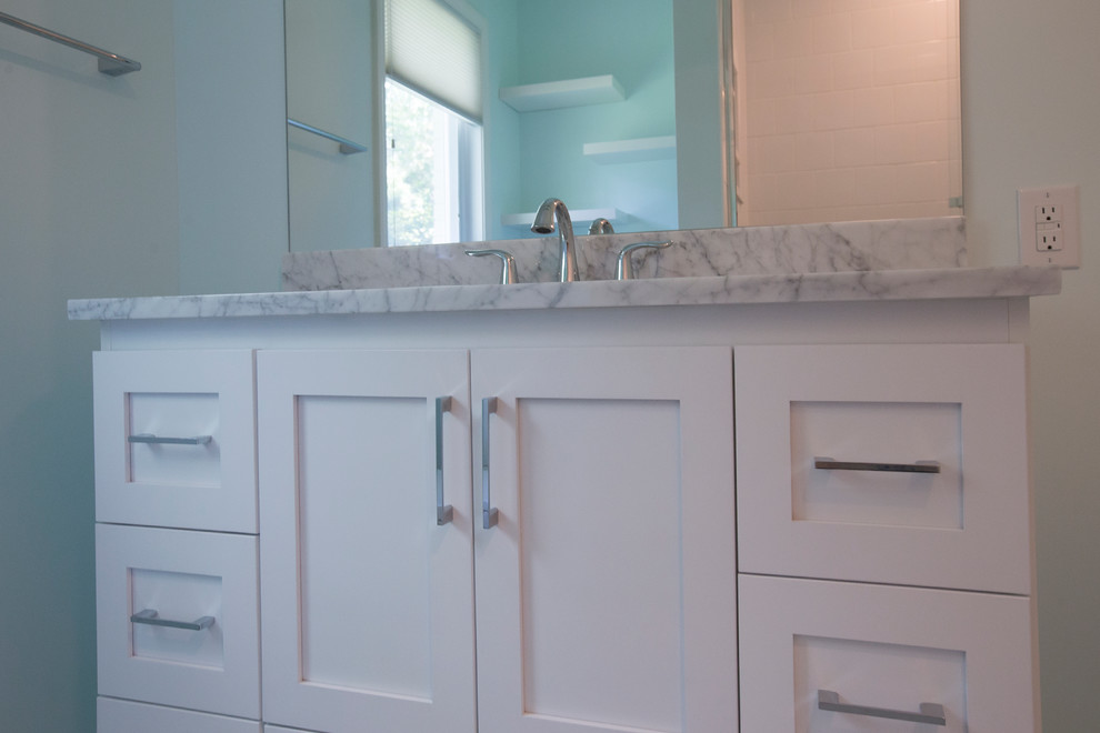 Photo of a small classic family bathroom in Raleigh with a submerged sink, shaker cabinets, white cabinets, marble worktops, an alcove bath, a shower/bath combination, a two-piece toilet, white tiles, blue walls, ceramic tiles, white floors, a sliding door, white worktops and ceramic flooring.