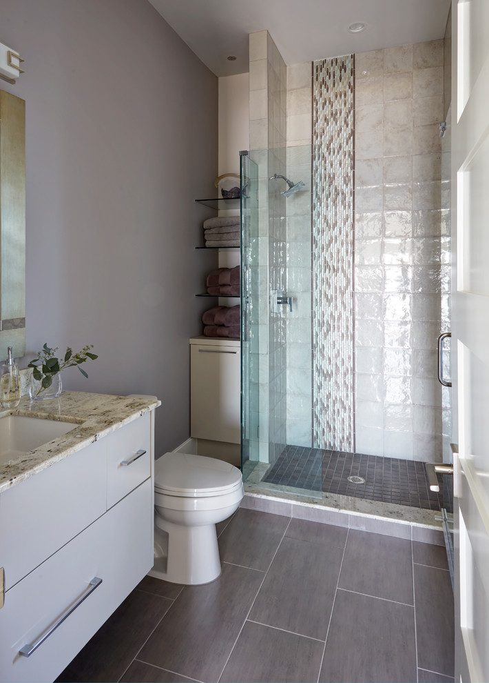 Photo of a large contemporary ensuite bathroom in Jacksonville with flat-panel cabinets, grey cabinets, a freestanding bath, a double shower, a one-piece toilet, beige tiles, porcelain tiles, beige walls, porcelain flooring, a vessel sink, marble worktops, white floors and an open shower.