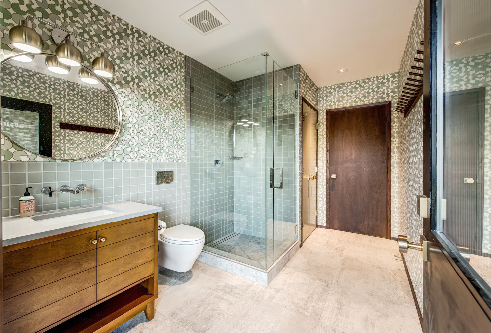 Photo of a medium sized eclectic family bathroom in Seattle with medium wood cabinets, a corner shower, a wall mounted toilet, green tiles, ceramic tiles, multi-coloured walls, beige floors, a hinged door, white worktops and wallpapered walls.