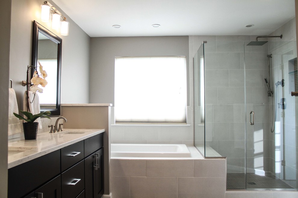 Cette photo montre une grande salle de bain principale tendance en bois foncé avec un placard à porte shaker, une baignoire posée, un lavabo encastré, un plan de toilette en quartz modifié, un carrelage gris et un mur gris.