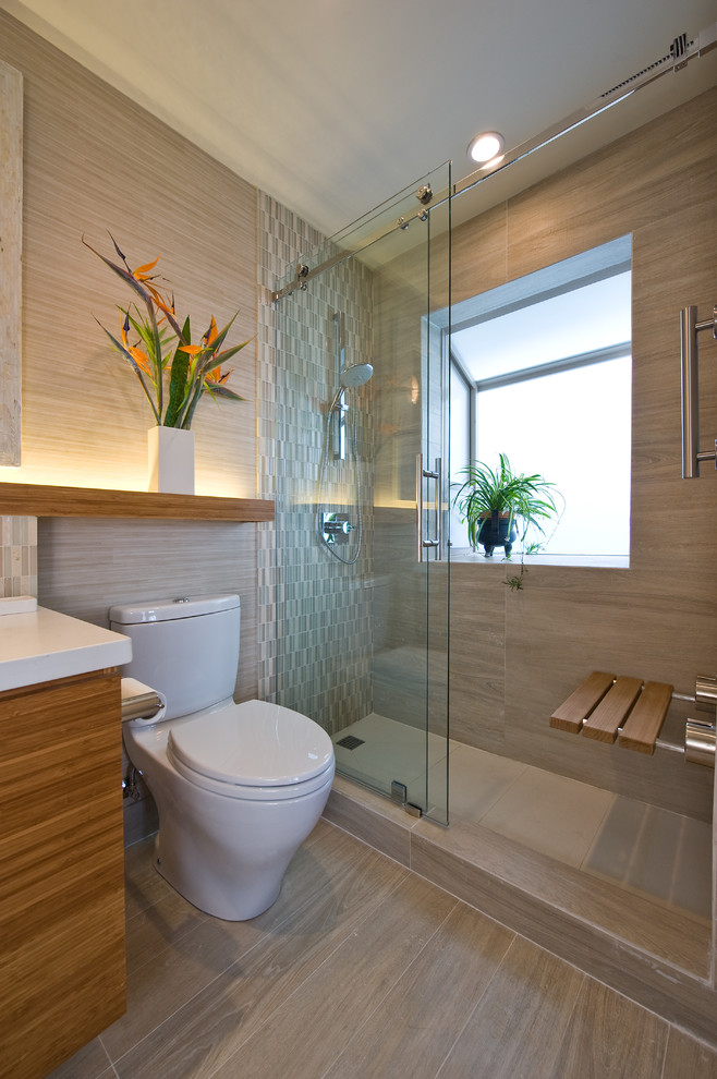 This is an example of a small contemporary shower room bathroom in Hawaii with flat-panel cabinets, engineered stone worktops, a walk-in shower, a one-piece toilet, beige tiles, mosaic tiles, beige walls, porcelain flooring, medium wood cabinets, beige floors and a sliding door.