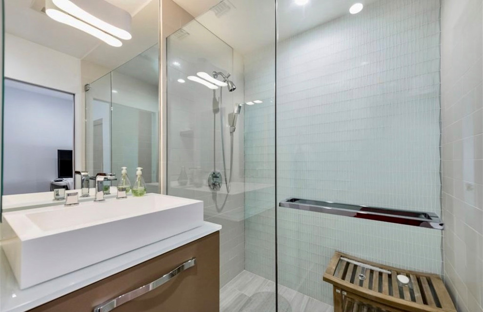 Идея дизайна: маленькая ванная комната в современном стиле с плоскими фасадами, серыми фасадами, душем без бортиков, унитазом-моноблоком, белой плиткой, стеклянной плиткой, белыми стенами, полом из керамогранита, душевой кабиной, настольной раковиной, стеклянной столешницей, серым полом, душем с распашными дверями, белой столешницей, тумбой под одну раковину и подвесной тумбой для на участке и в саду