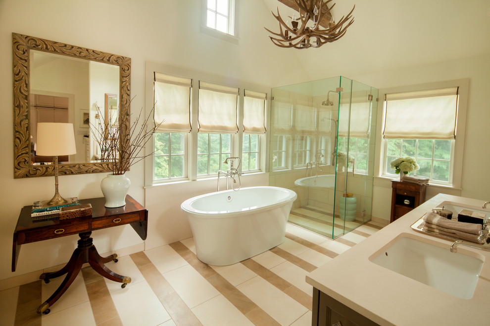 Inredning av ett klassiskt en-suite badrum, med ett fristående badkar, ett undermonterad handfat, beige skåp, en hörndusch, kalkstensgolv, beiget golv och dusch med gångjärnsdörr