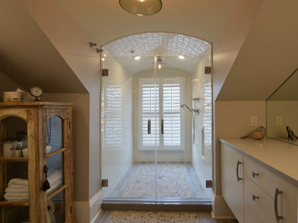 На фото: большая главная ванная комната в стиле неоклассика (современная классика) с плоскими фасадами, белыми фасадами, душем в нише, керамической плиткой, полом из галечной плитки, столешницей из искусственного камня и серыми стенами с