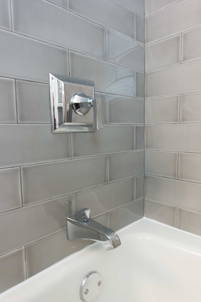 Klassisk inredning av ett mellanstort en-suite badrum, med luckor med infälld panel, grå skåp, ett badkar i en alkov, en toalettstol med separat cisternkåpa, grå väggar, klinkergolv i keramik, ett undermonterad handfat, bänkskiva i akrylsten, grått golv och dusch med duschdraperi
