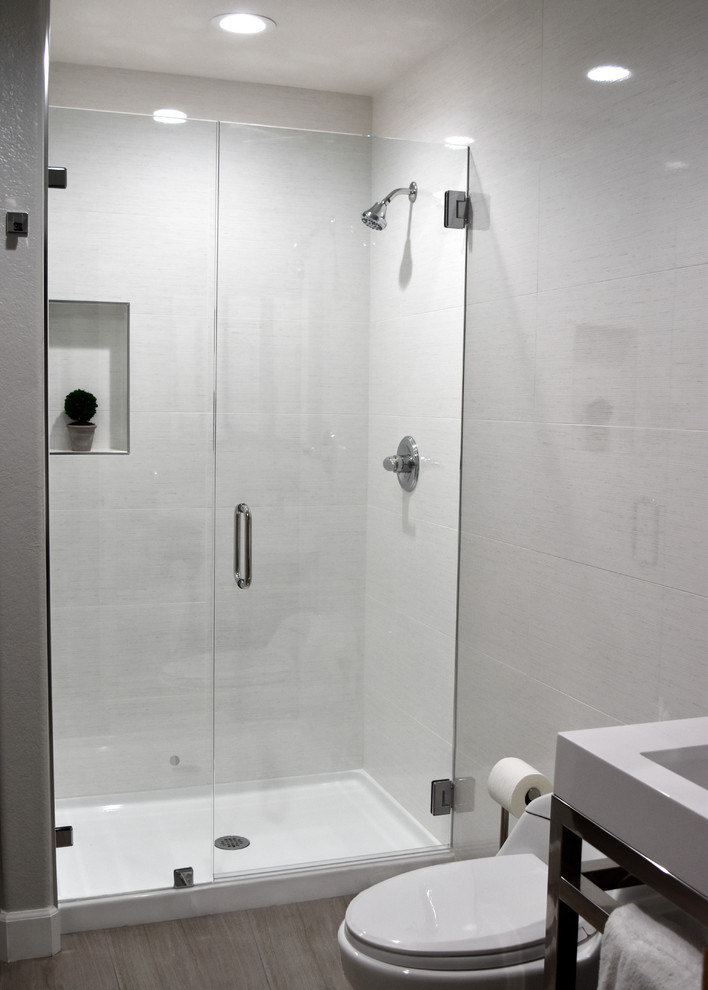 Idéer för ett litet modernt badrum med dusch, med en toalettstol med hel cisternkåpa, vit kakel, porslinskakel, vita väggar, klinkergolv i porslin, ett integrerad handfat, brunt golv, dusch med gångjärnsdörr, öppna hyllor, bänkskiva i akrylsten och en dusch i en alkov
