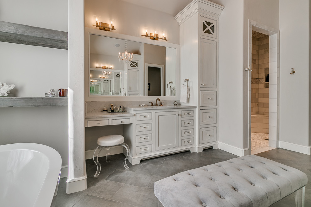 Large farmhouse ensuite wet room bathroom in Oklahoma City with beaded cabinets, white cabinets, a freestanding bath, a one-piece toilet, white tiles, marble tiles, beige walls, porcelain flooring, a submerged sink, marble worktops, grey floors and an open shower.