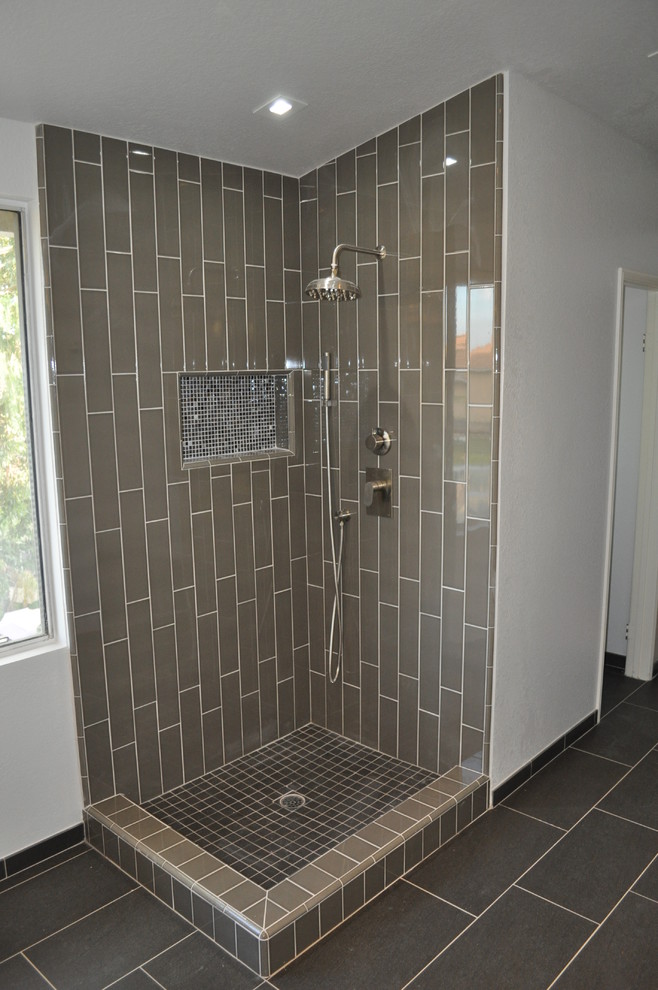 Photo of a modern bathroom in Los Angeles with freestanding cabinets, dark wood cabinets, engineered stone worktops, a freestanding bath, a corner shower, grey tiles, porcelain tiles, grey walls and porcelain flooring.