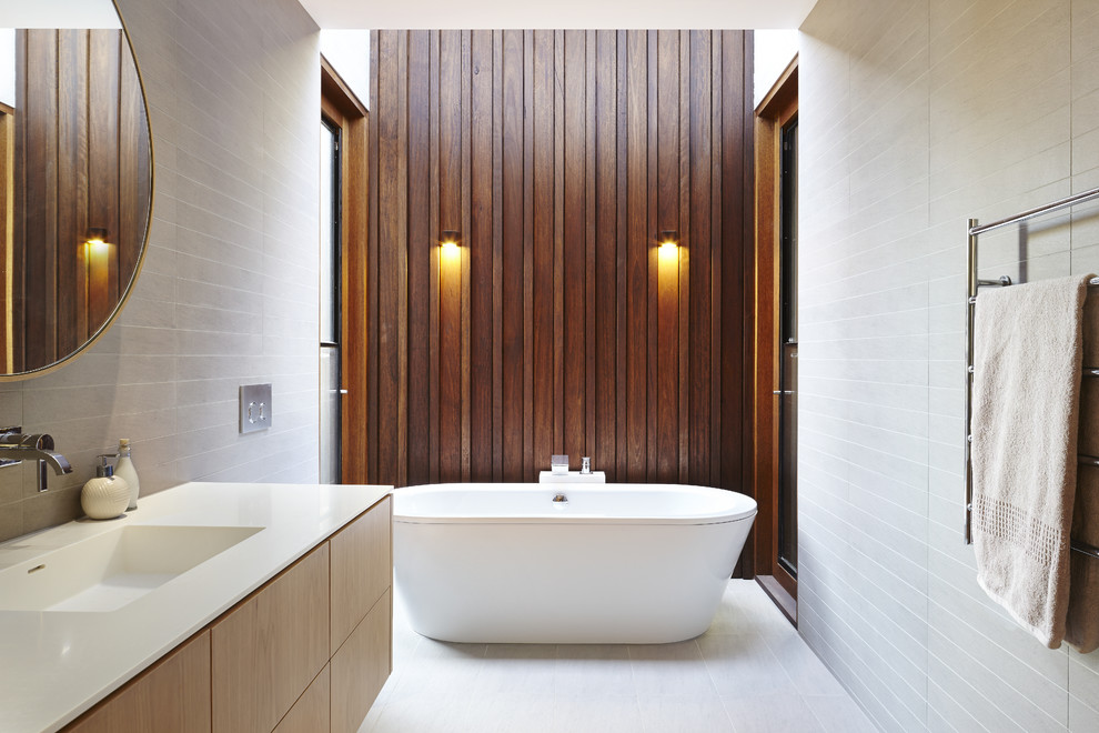 メルボルンにある広いコンテンポラリースタイルのおしゃれなマスターバスルーム (淡色木目調キャビネット、置き型浴槽、アルコーブ型シャワー、白いタイル、一体型シンク、フラットパネル扉のキャビネット) の写真