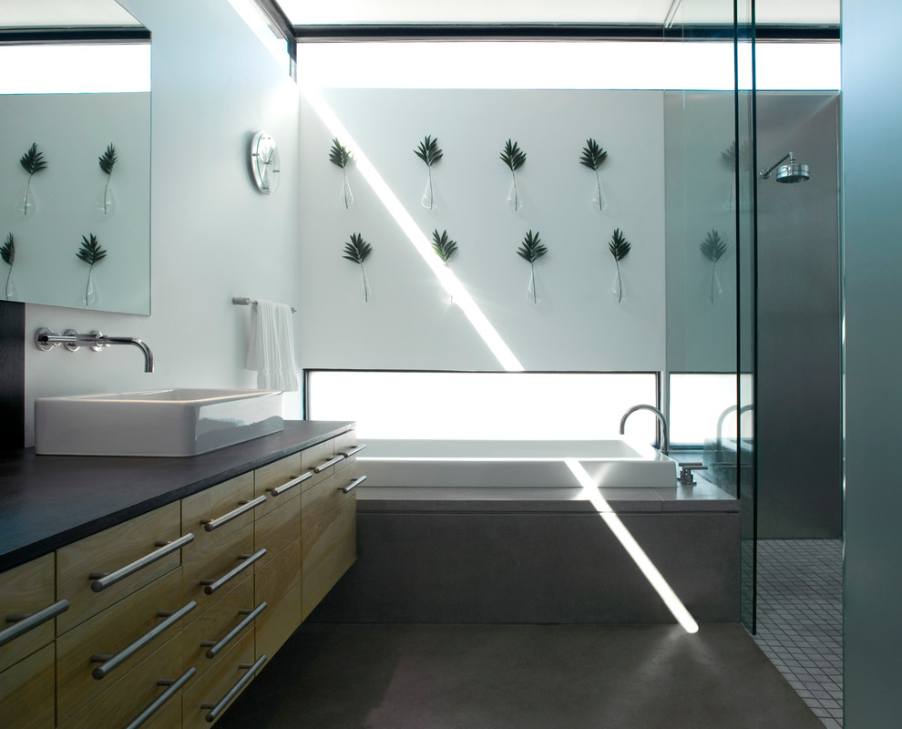 Inspiration for a medium sized modern ensuite bathroom in Phoenix with flat-panel cabinets, light wood cabinets, a built-in bath, a built-in shower, a two-piece toilet, grey tiles, mosaic tiles, white walls, concrete flooring, a vessel sink and concrete worktops.