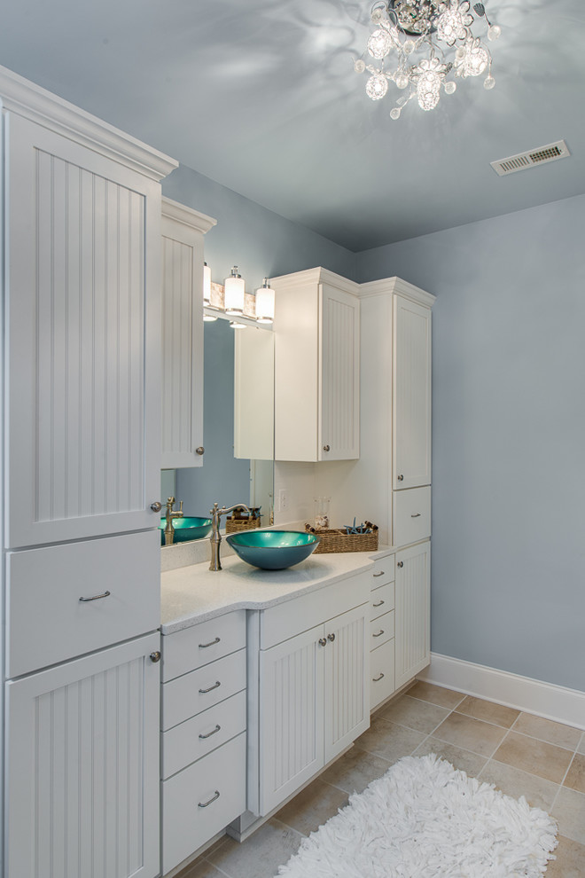 Design ideas for a large beach style bathroom in Charlotte with beaded cabinets, white cabinets, beige tiles, ceramic tiles, blue walls, ceramic flooring, a vessel sink and solid surface worktops.