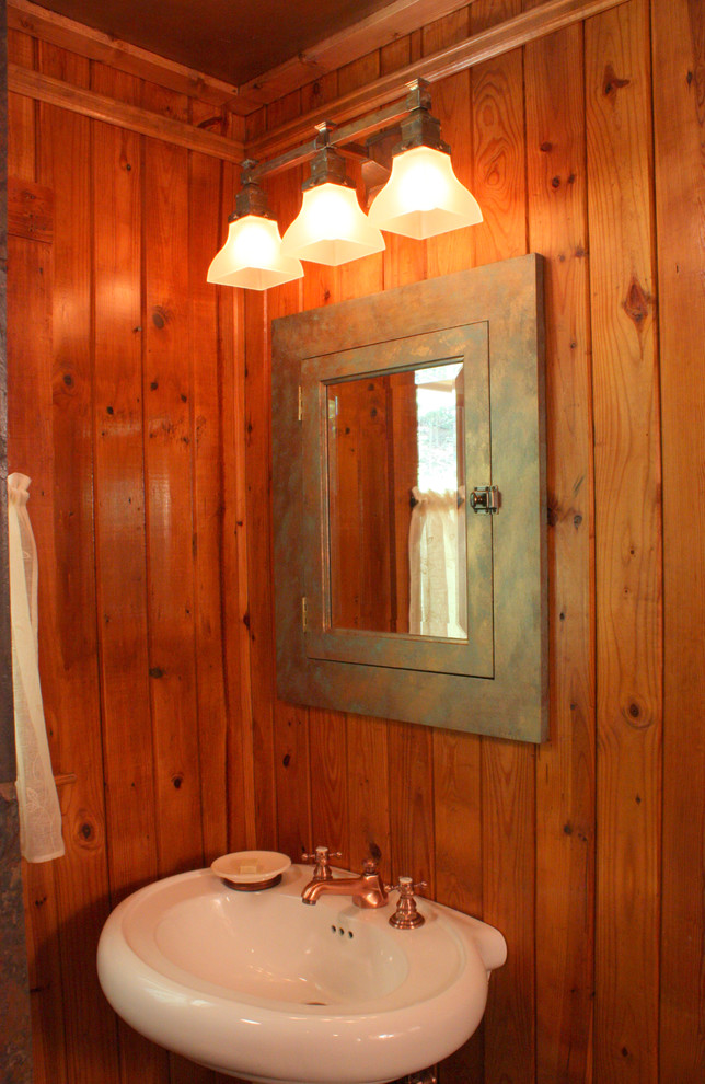 Imagen de cuarto de baño principal rural de tamaño medio con sanitario de una pieza, paredes blancas, suelo de madera en tonos medios y lavabo con pedestal