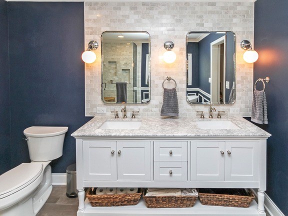 Example of a large transitional master beige tile and stone tile porcelain tile and brown floor bathroom design in Charlotte with shaker cabinets, white cabinets, a two-piece toilet, blue walls, an undermount sink, marble countertops and a hinged shower door