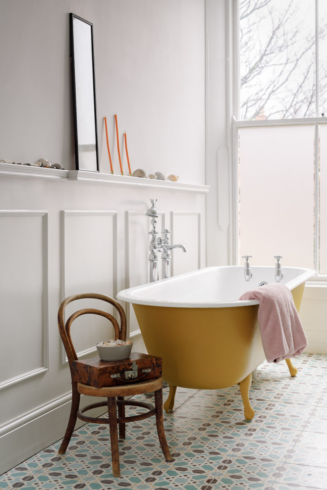 Cette image montre une salle de bain bohème avec une baignoire sur pieds, un mur blanc, un sol multicolore et boiseries.