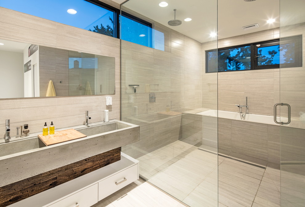Idéer för funkis badrum, med släta luckor, vita skåp, ett undermonterat badkar, våtrum, grå kakel, ett avlångt handfat, bänkskiva i betong och dusch med gångjärnsdörr