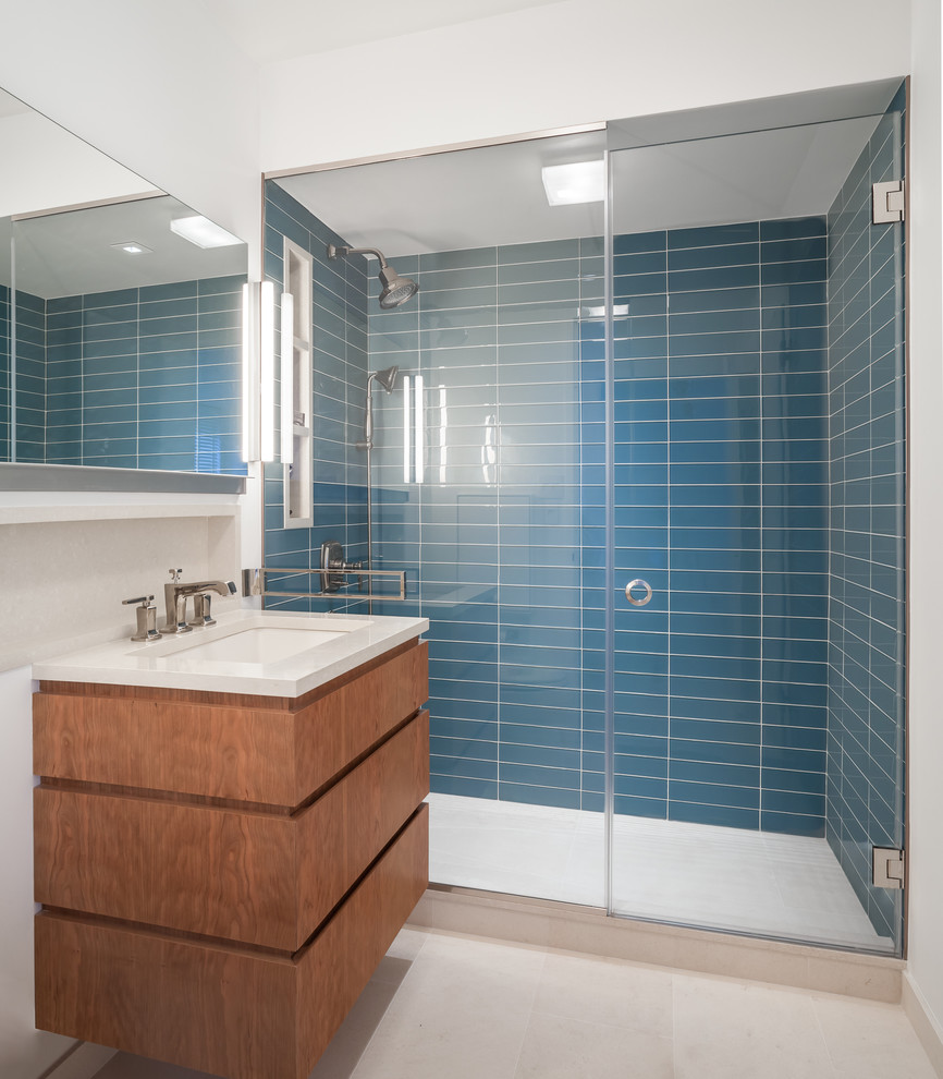 Exempel på ett mellanstort modernt en-suite badrum, med ett undermonterad handfat, släta luckor, skåp i mellenmörkt trä, bänkskiva i kvarts, en dusch i en alkov, blå kakel, glaskakel, vita väggar och kalkstensgolv